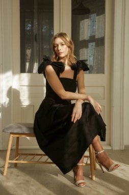 Omuz kemerlerinde fiyonkları olan zarif siyah Midi elbiseli kadın modellerin fotoğrafları.
