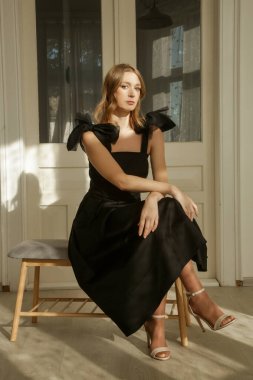 Omuz kemerlerinde fiyonkları olan zarif siyah Midi elbiseli kadın modellerin fotoğrafları.