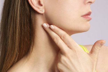 Beyaz kadın boğazına dokunuyor. Boğaz ağrısı, soğuk algınlığı, grip, bademcik iltihabı veya tiroid bezi sorunu