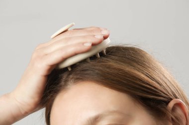 Kafa masajı yapan bir kız kafa masajı yapıyor, saç büyümesini teşvik ediyor, mikro dolaşımı sağlıyor, doğal yağları kafa derisine daha eşit dağıtmaya yardımcı oluyor.