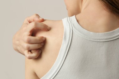 Kürek kemiğini tırmalayan kadın, parestezi semptomu.