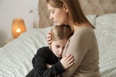 Sevgi dolu anne üzgün küçük kızını teselli ediyor.