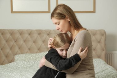 Sevgi dolu anne üzgün küçük kızını teselli ediyor.