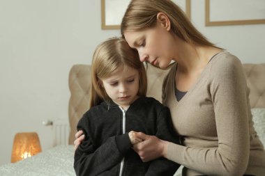 Sevgi dolu anne üzgün küçük kızını teselli ediyor.