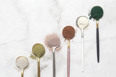 Sağlık ve güzellik için farklı beslenme malzemeleri - kolajen, vitamin, biyotin, kaşıklardaki protein tozu