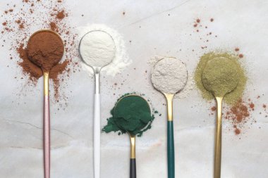 Sağlık ve güzellik için farklı beslenme malzemeleri - kolajen, vitamin, biyotin, kaşıklardaki protein tozu