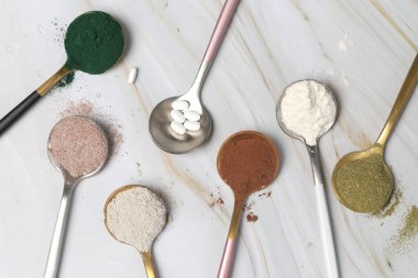 Sağlık ve güzellik için farklı beslenme malzemeleri - kolajen, vitamin, biyotin, kaşıklardaki protein tozu