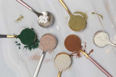 Sağlık ve güzellik için farklı beslenme malzemeleri - kolajen, vitamin, biyotin, kaşıklardaki protein tozu