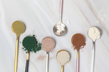 Sağlık ve güzellik için farklı beslenme malzemeleri - kolajen, vitamin, biyotin, kaşıklardaki protein tozu