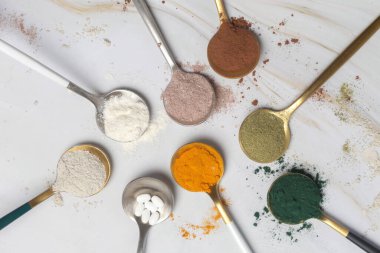 Sağlık ve güzellik için farklı beslenme malzemeleri - kolajen, vitamin, biyotin, kaşıklardaki protein tozu