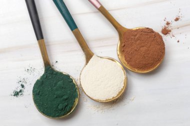 Sağlık ve güzellik için farklı beslenme malzemeleri - kolajen, vitamin, biyotin, kaşıklardaki protein tozu