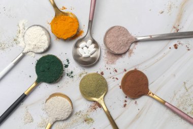 Sağlık ve güzellik için farklı beslenme malzemeleri - kolajen, vitamin, biyotin, kaşıklardaki protein tozu