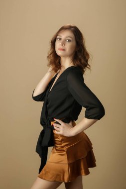 Siyah bluz ve bej mini etek giyen kadın model. Şık ve şık bir kıyafet. Moda Stüdyosu çekimi.