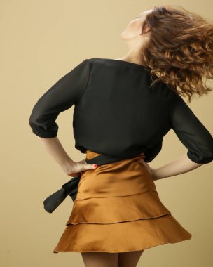 Siyah bluz ve bej mini etek giyen kadın model. Şık ve şık bir kıyafet. Moda Stüdyosu çekimi.