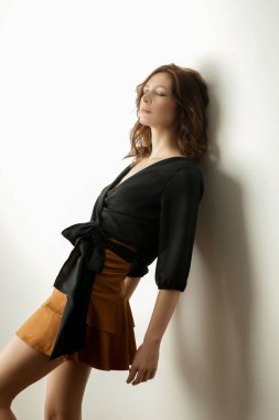 Siyah bluz ve bej mini etek giyen kadın model. Şık ve şık bir kıyafet. Moda Stüdyosu çekimi.