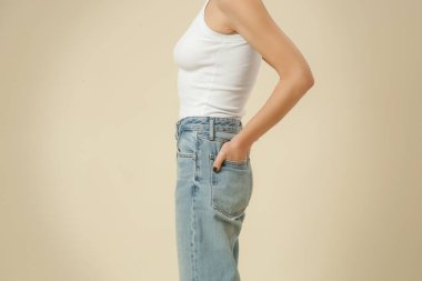 Klasik kıyafetli bir kadının stüdyo fotoğrafları. Mavi kot pantolon ve beyaz atlet.