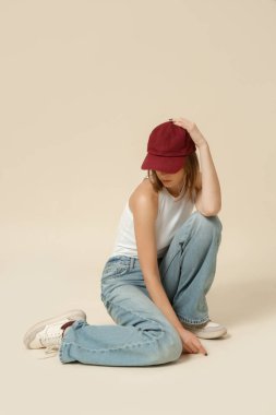 Klasik kıyafetli bir kadının seri fotoğrafları. Mavi kot pantolon, beyaz atlet ve kırmızı beysbol şapkası.