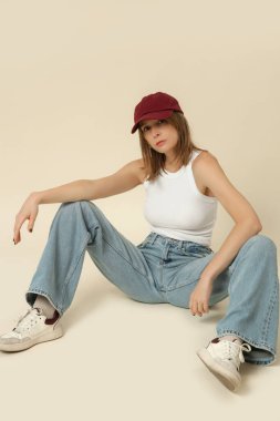Klasik kıyafetli bir kadının seri fotoğrafları. Mavi kot pantolon, beyaz atlet ve kırmızı beysbol şapkası.