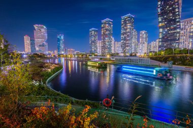 Sonbaharda gece manzarası ve Songdo Bölgesi, Incheon Güney Kore 'deki Songdo Central Park' ta güzel ışıklandırılmış turist tekneleri..