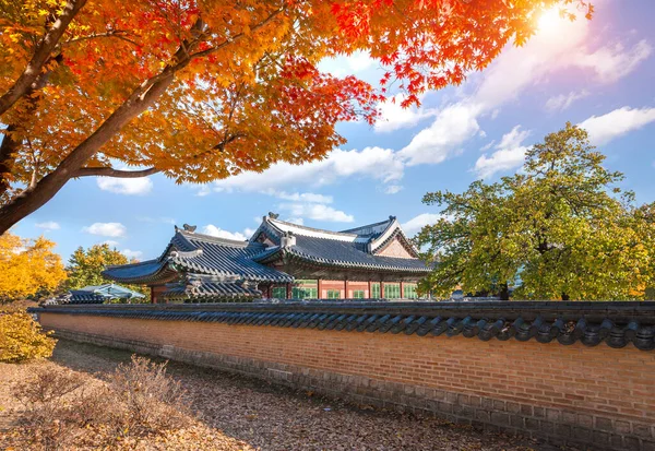 Gyeongbokgung Palace in autumn with maple leaves in the foreground, South Korea.