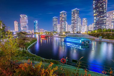 Sonbaharda gece manzarası ve Songdo Bölgesi, Incheon Güney Kore 'deki Songdo Central Park' ta güzel ışıklandırılmış turist tekneleri..