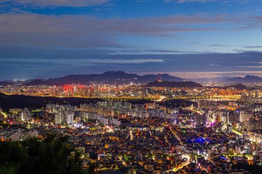Seul şehrinin silueti ve gökdelenleri gece Namsan Dağı ve Bukhansan arka planda, Seul, Güney Kore.