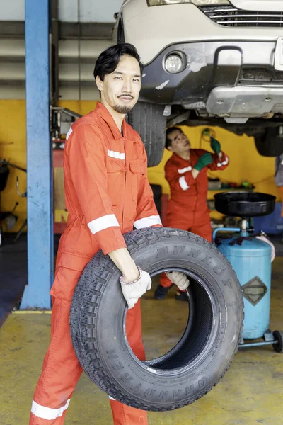 Hardworking experienced worker holding tire and he wants to change it In the tire store. Selective focus.
