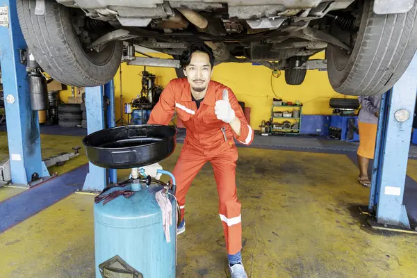 Male mechanic engineering working under Vehicle in Car Service. Repair specialist, technical maintenance. Small business owner. He is doing a vehicle inspection. Selective Focus