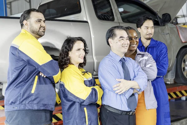 Group of mechanics men and woman arm crosses to work success at auto service garage. Staff car service team worker maintenance and repair vehicle. Selective Focus