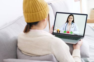 Asyalı kadın hasta dijital tablet, teletıp, eczacı, sağlık hizmetleri hakkında danışmanlık yapıyor.