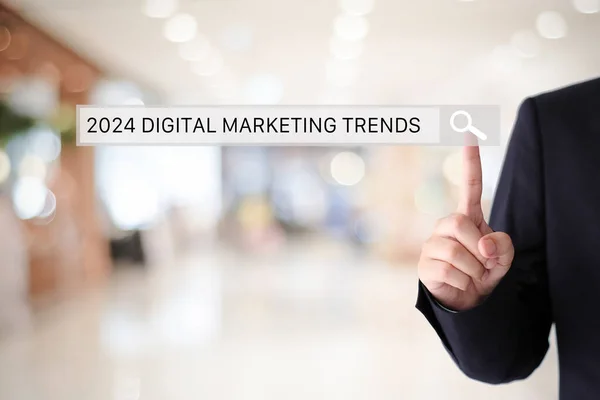 Businesman hand touching 2024 digital marketing trends search bar over blur office background, banner, SEO 2024 business trends planning, success in business concept