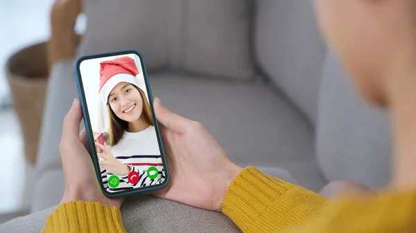 Asian woman video call for greeting in Christmas celebration, Woman hand holding smart phone while talking with friend in Christimas season, new normal, online party celebrating