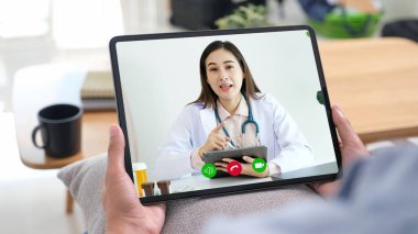 Asyalı kadın hasta dijital tablet, teletıp, eczacı, sağlık hizmetleri hakkında danışmanlık yapıyor.