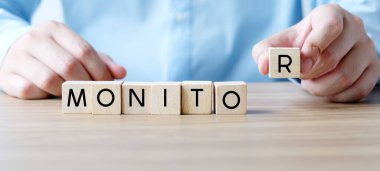 İş adamı elinde tahta bloklarla monitör sözcüğü, iş afişi taşıyor.