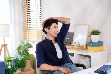 Ofiste çalışırken gülümseyen genç adam. 