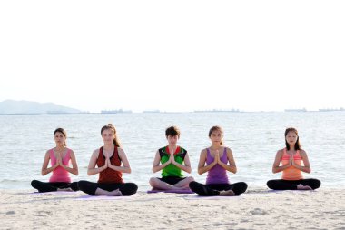 Sahilde yoga yapan bir grup sağlıklı genç insan, sağlıklı yaşam tarzları, sağlık, refah...
