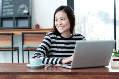 Genç Asyalı kadın sıradan yaşam tarzlarında dizüstü bilgisayar kullanıyor, insanlar ve teknoloji, yaşam tarzları