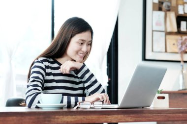 Genç Asyalı kadın sıradan yaşam tarzlarında dizüstü bilgisayar kullanıyor, insanlar ve teknoloji, yaşam tarzları