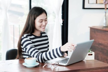 Genç Asyalı kadın sıradan yaşam tarzlarında dizüstü bilgisayar kullanıyor, insanlar ve teknoloji, yaşam tarzları