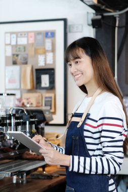 Genç asyalı kadın, barista, kafe sayaç arka plan, yiyecek ve içecek kavramı kahve siparişalmak için tablet kullanarak