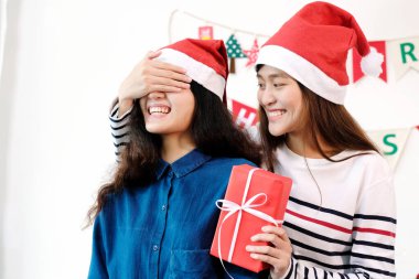 İki genç Asyalı kadın sürpriz Noel hediyesi veriyor, Noel kutlaması çifti, LGBT ve arkadaş konsepti