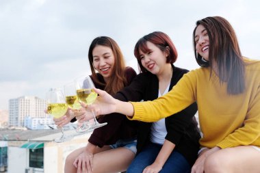 Bir grup Asyalı genç kadın çatıda yeni yıl partisinde içiyor, arkadaşlar tatilde kutlama partisi konsepti