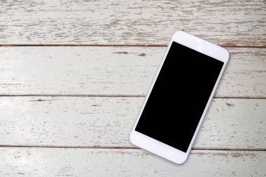 Boş ekranda sahte kadar şablonla kopya alanı, üstten görünüm, düz yatıyordu teknoloji ve yaşam tarzı için vintage beyaz tahta arka plan ile beyaz akıllı telefon 