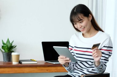 Genç Asyalı kadın kredi kartı tutuyor ve kafede alışveriş için tablet kullanıyor, iş ve teknoloji konsepti, dijital pazarlama, günlük yaşam tarzı