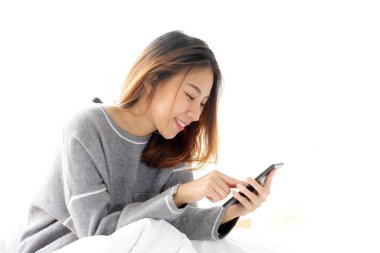 Genç Asyalı kadın akıllı telefon kullanıyor. Beyaz arka planda rahatlama duygusu, telefondaki insanlar, yaşam tarzı.