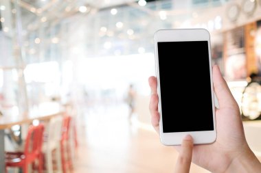 Kafe arka planında boş ekranı olan akıllı bir telefon. Model, şablon, restoran rezervasyonu, internetten yemek teslimatı konsepti.