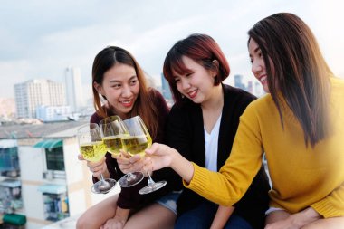 Bir grup Asyalı kadın çatıdaki partide içiyor, açık havada kutlama yapıyorlar. 