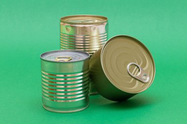 Yeşil Arkaplanda Boş Kenarlı İstiflenmiş Teneke Kutular Grubu. Konserve yiyecekler. Güvenli ve uzun vadeli yiyecek depolamak için farklı alüminyum kutular. Çelik Mühürlü Yiyecek Depolama Kutuları