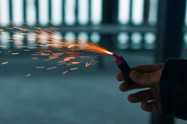 Firecracker 'ı kıvılcımla yakmak. Elinde Petard tutan bir adam. Gürültülü ve tehlikeli yeni yıl eğlencesi. Havai fişeklerle holiganlık. Halka açık yerlerde havai fişek sesleri