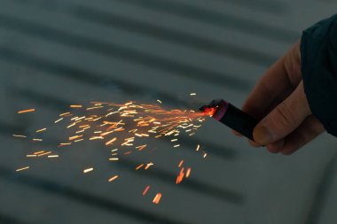 Firecracker 'ı kıvılcımla yakmak. Elinde Petard tutan bir adam. Gürültülü ve tehlikeli yeni yıl eğlencesi. Havai fişeklerle holiganlık. Halka açık yerlerde havai fişek sesleri